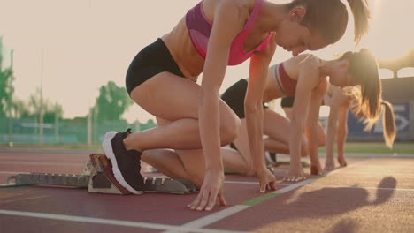 Three-female-athletes-simultaneously-start-running-marathon-rivalry-slow-motion.-women-standing-on-a-starting-line-before-race